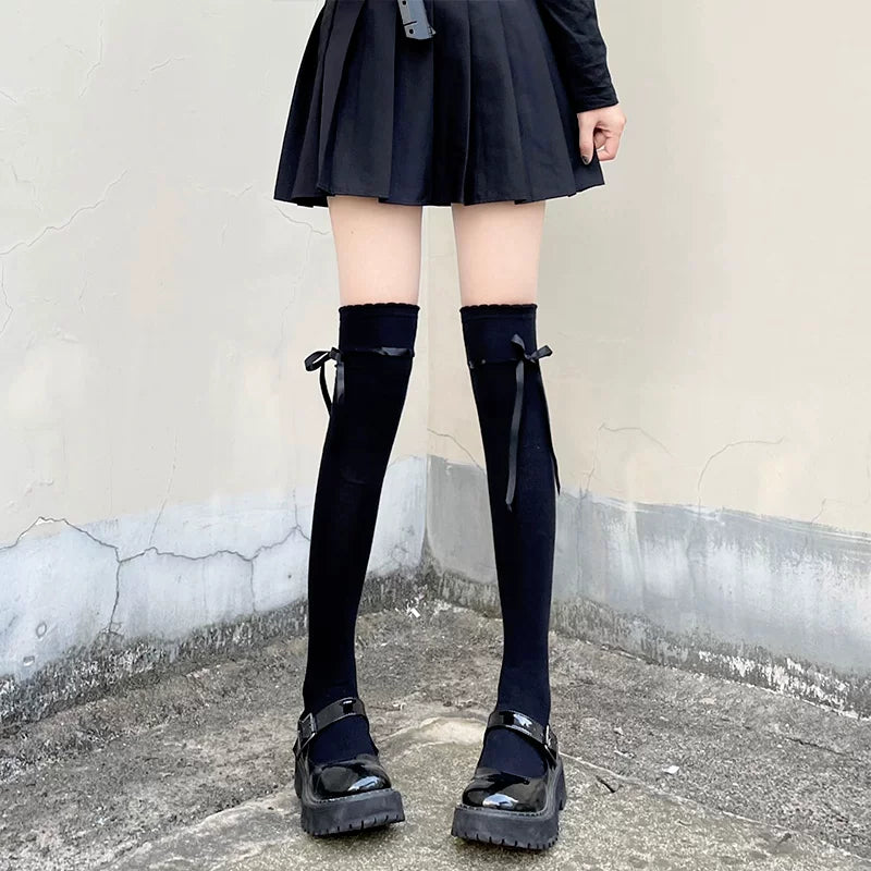 Floral Milk Cat black over-knee socks with side ties styled with a pleated black skirt.