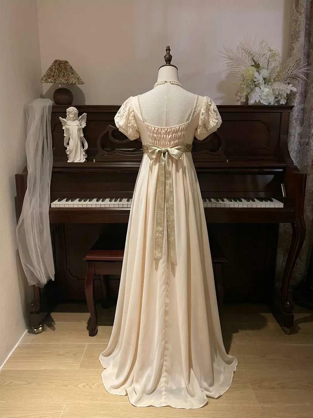 Ivory OP dress with puff sleeves, a lace front panel and a tie bow shown on a mannequin.