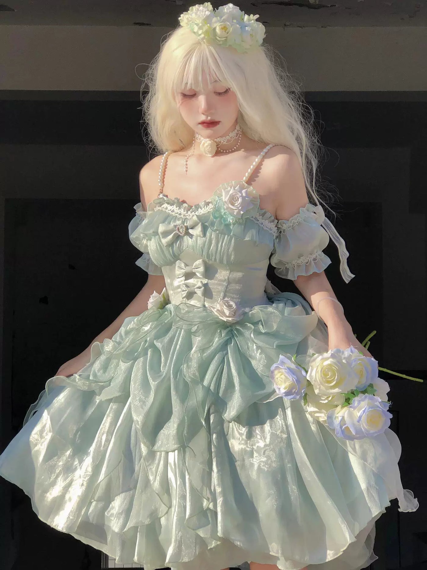 Model wearing a pale green JSK with layered ruffles, bows and floral appliqués.