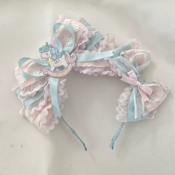 Pastel pink-and-blue lace headband with a rocking-horse motif and ribbon ties