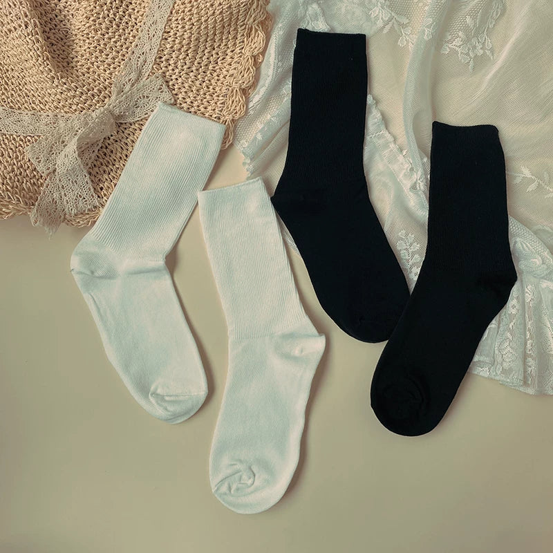 White and black vertical-ribbed mid-calf socks arranged in a flat lay