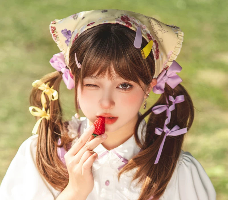 Model wearing a printed triangular headscarf with decorative hair accessories in a soft outdoor portrait.
