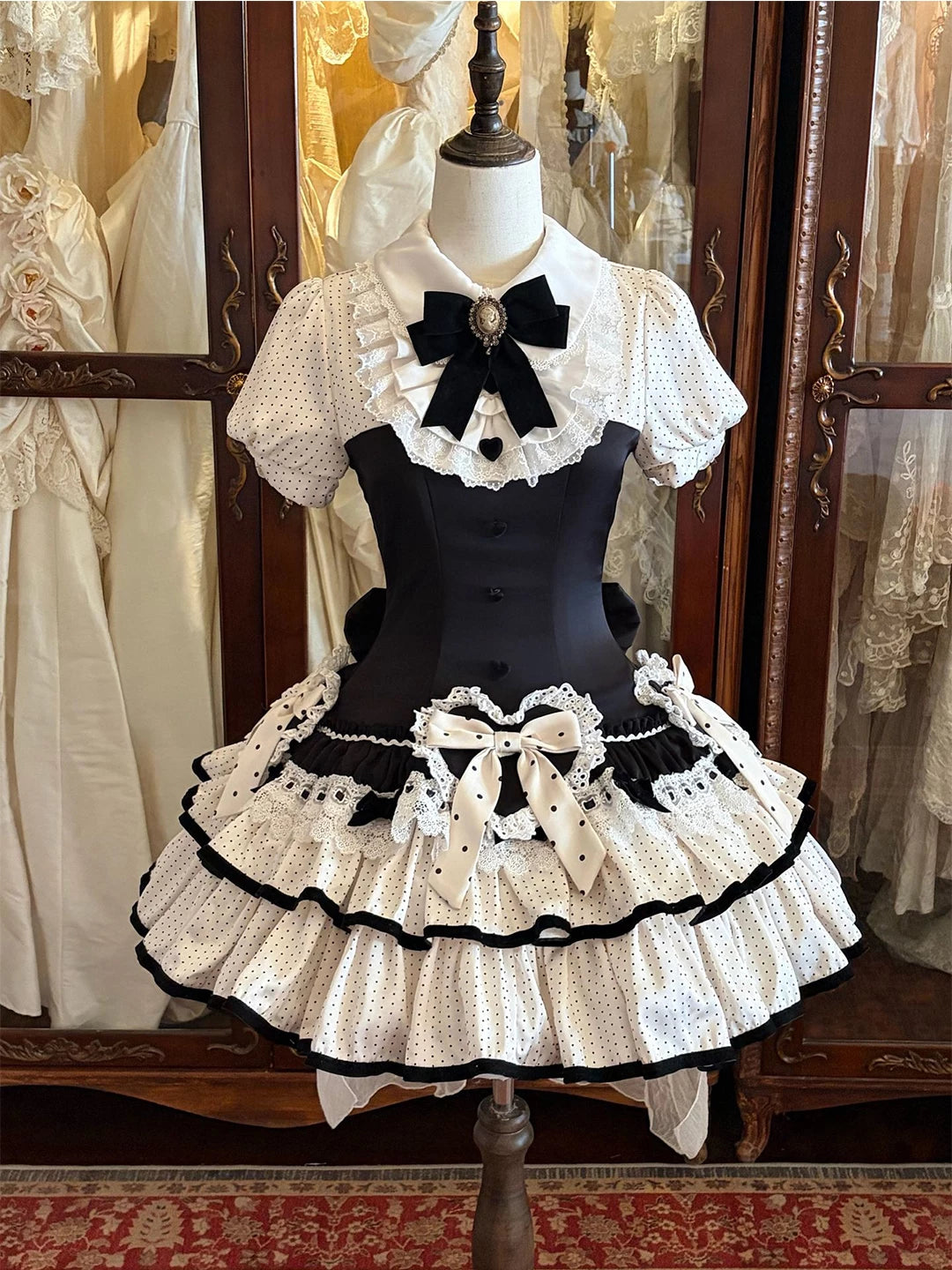 Black-and-white polka-dot OP dress with puff sleeves, tiered skirt and bows displayed on a mannequin.