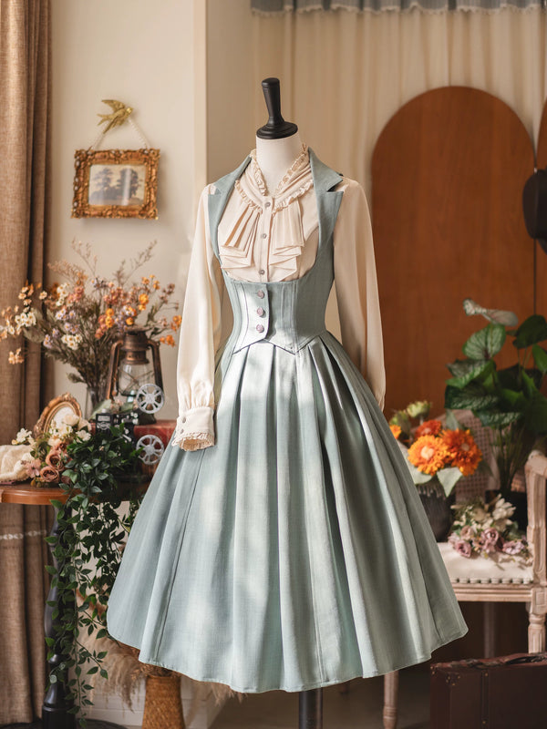 Forest Wardrobe Zhiqiu light slate-blue one-piece dress with a fitted waist panel, pleated skirt and ruffled apricot-colored shirt on a mannequin.
