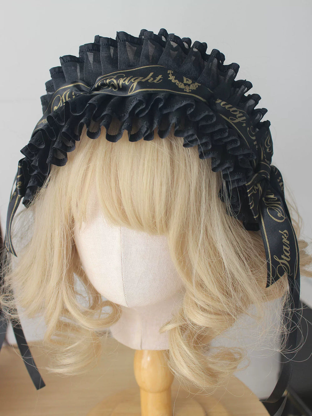 Black-and-gold ruffled bow headwear and accessory options displayed on mannequins.