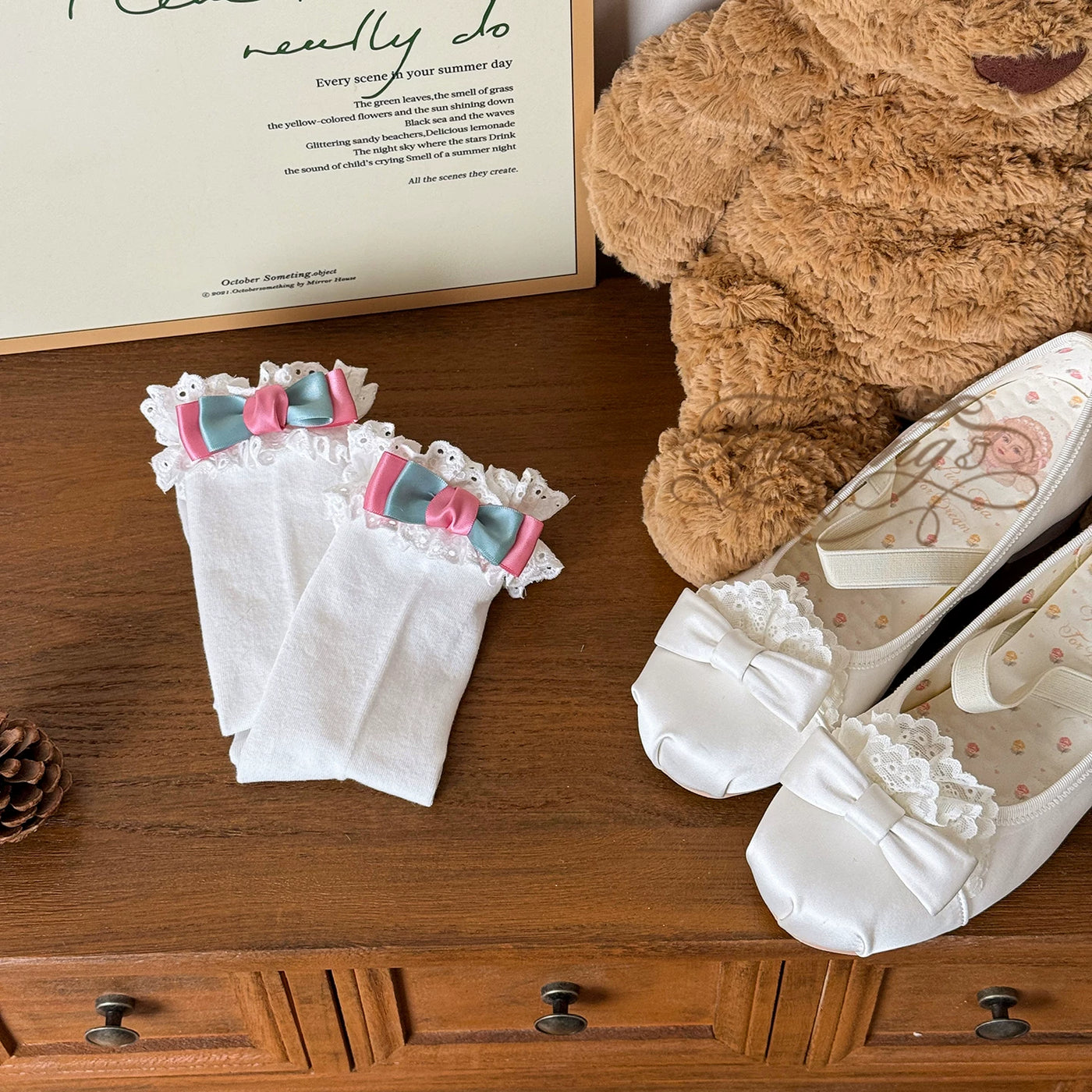 White mid-calf socks with lace cuffs and blue-pink bow accents styled with a pale Lolita outfit.