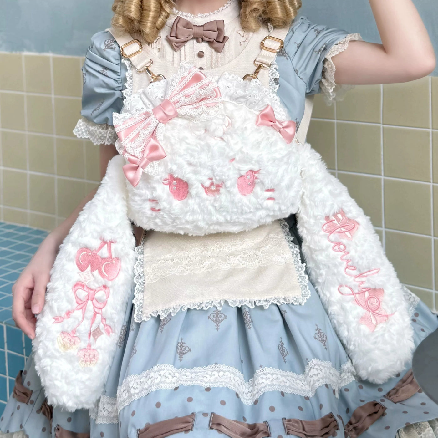 White plush rabbit backpack with lace edging and pink bows shown on a model.