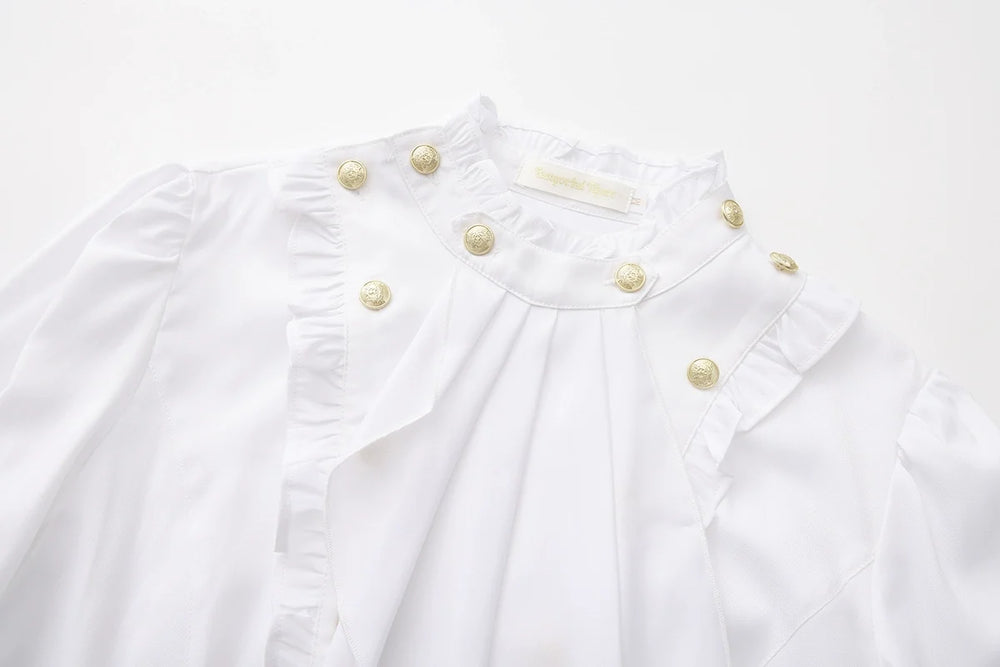 White Ouji blouse close-up with metallic buttons and ruffled front