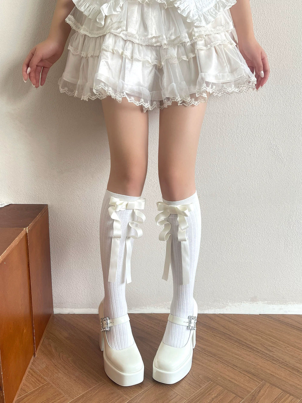 White mid-calf socks with oversized ribbon bows and long trailing ties worn with a Lolita outfit