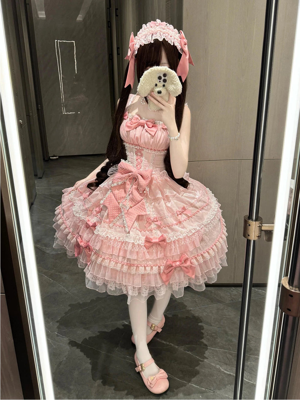 Creamy pink JSK dress with layered lace, ruffles, and bows, shown in a mirror.