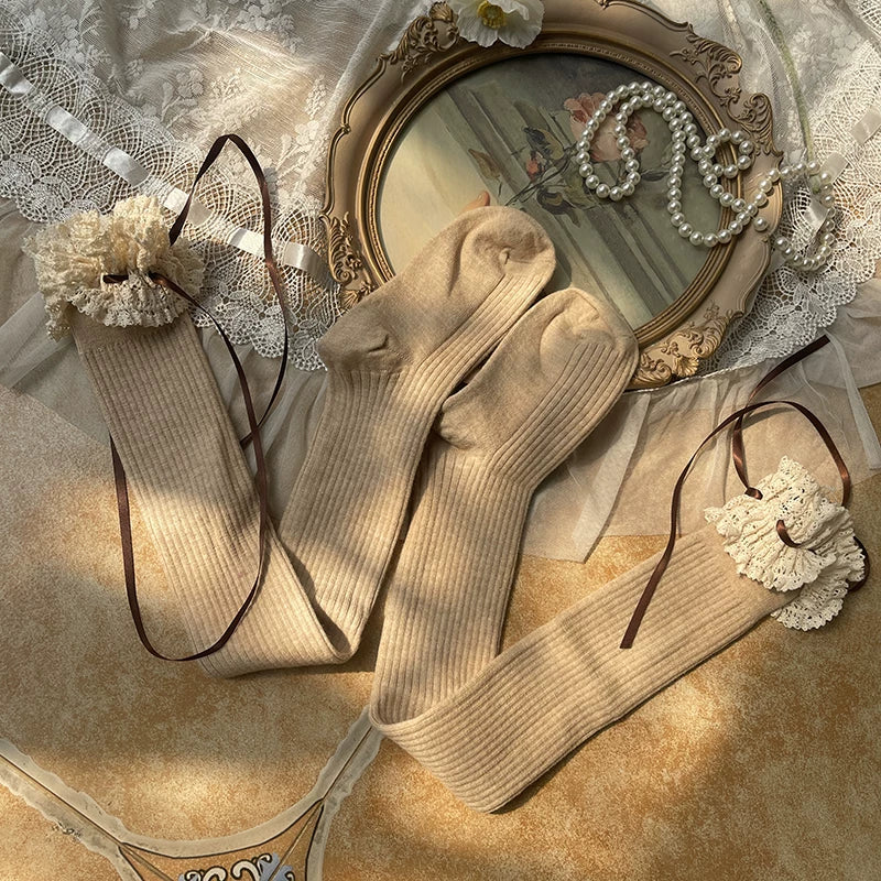 White thigh-high socks with wide lace trim and ribbon ties in a Lolita-style coordinate.