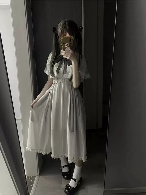 White lace dress with a sheer cape overlay and dark bow tie shown on a model