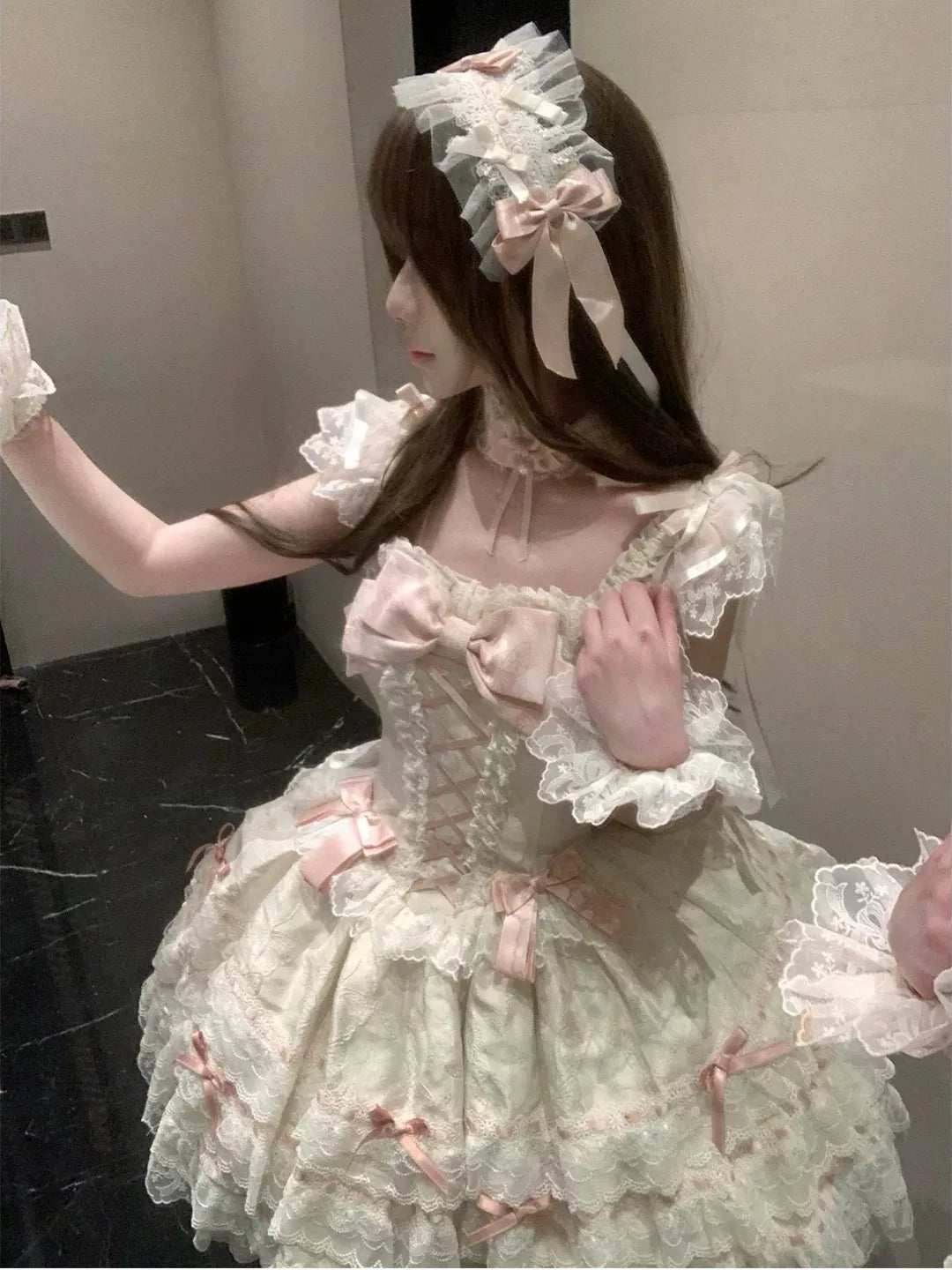 Apricot JSK dress with layered lace ruffles and pink bows styled on a model