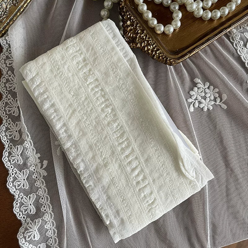 Creamy white floral-jacquard tights shown beneath a white lace-trimmed skirt.