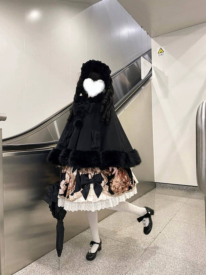 Black Kitty Pompom cape shown in a styled supplier photo; coordinating clothing and props are not included.