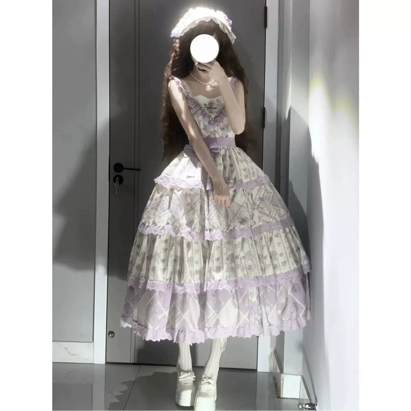 Model wearing a pale purple and cream tiered JSK dress with lace trim and a waist bow.