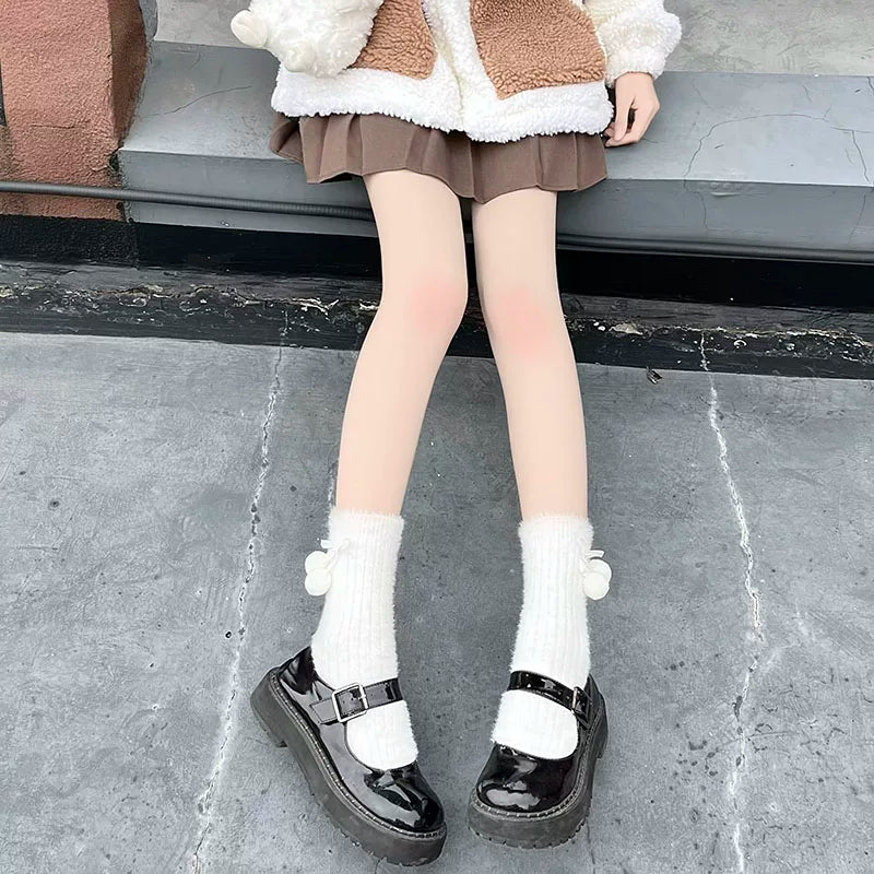 White ribbed socks with pom-pom accents worn with black Mary Jane shoes