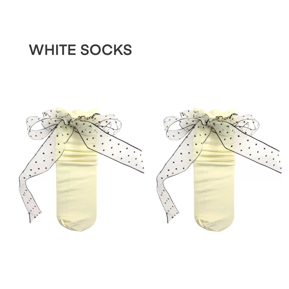 Milky white mid-calf socks with black polka-dot bows and ruffled cuffs displayed on a white background.