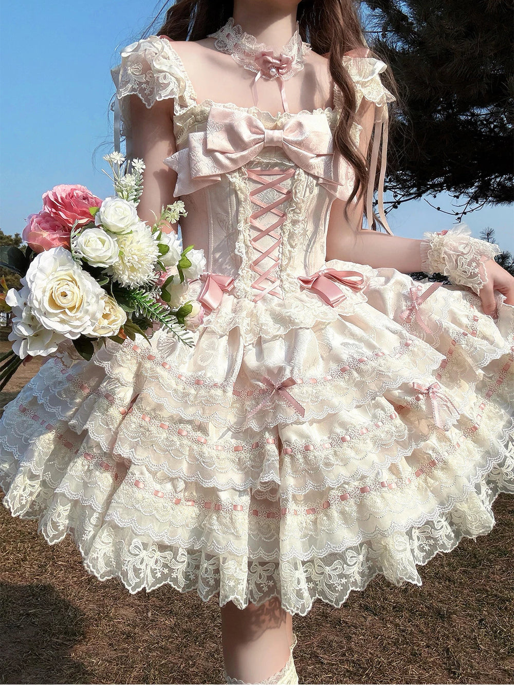 Apricot lace JSK dress with large blush bow and layered skirt worn outdoors.