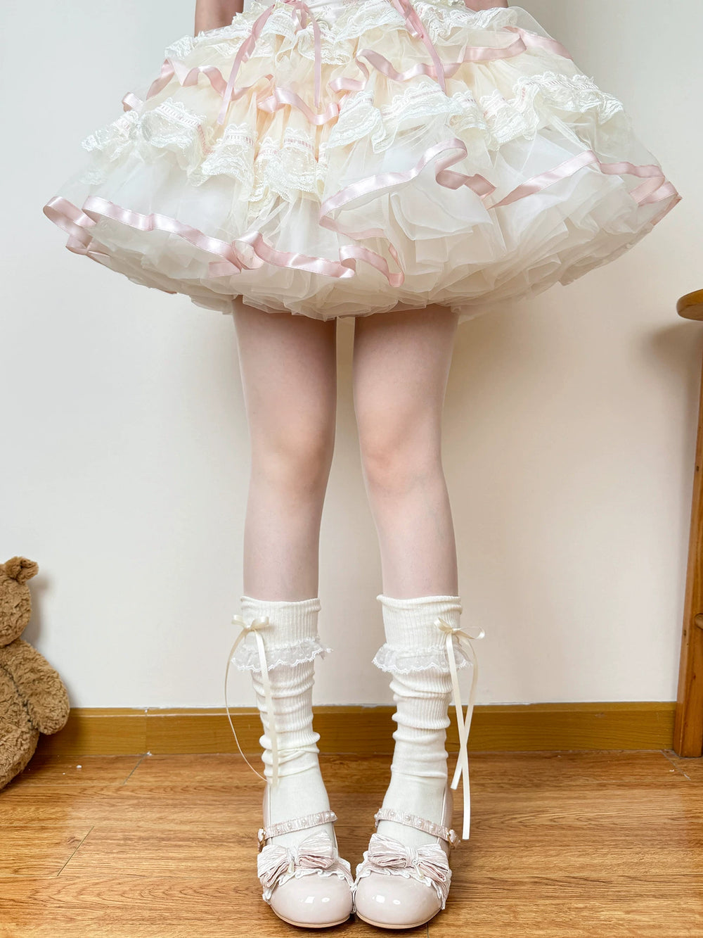 White slouch socks with lace-trimmed cuffs and long ribbon bows styled beneath a pale dress.