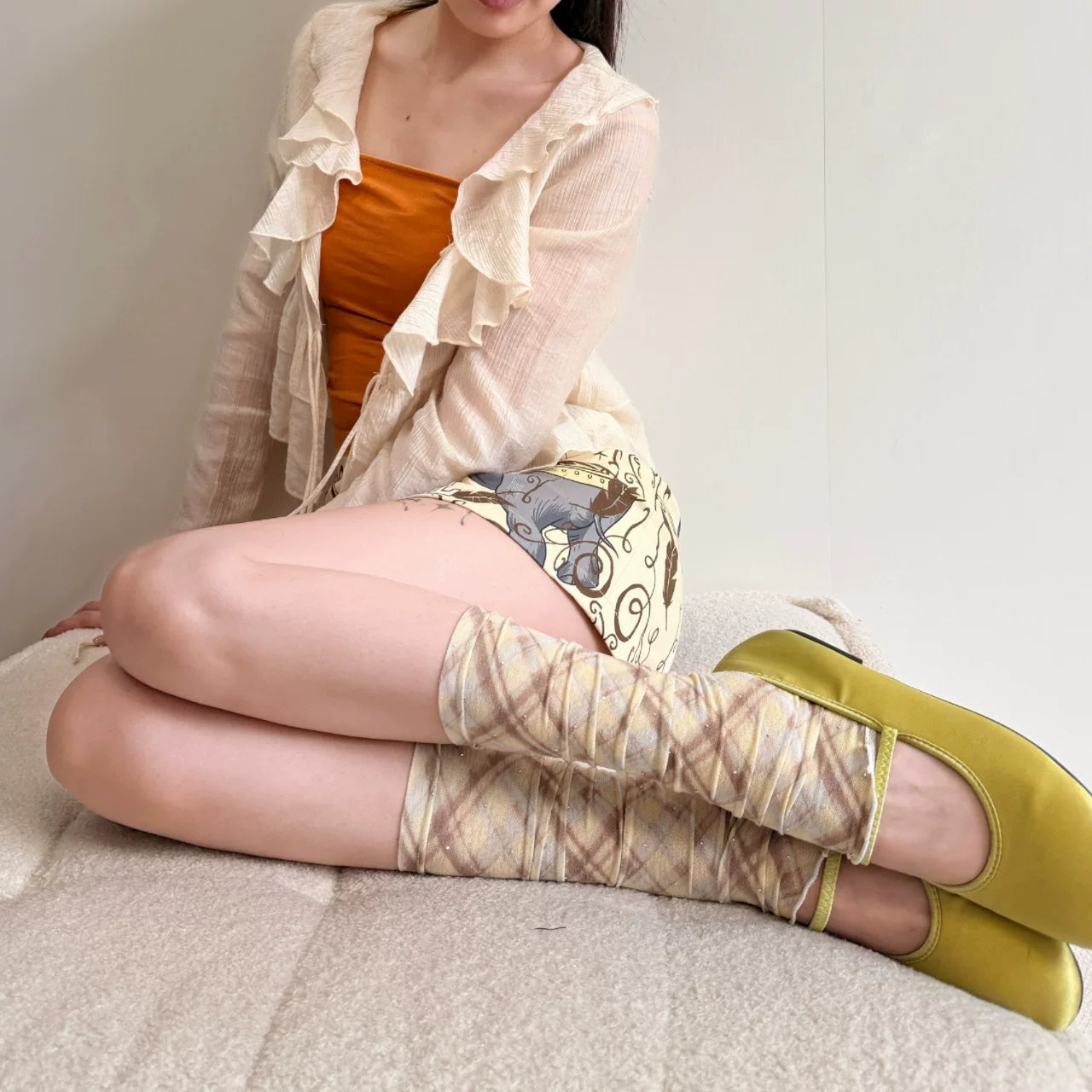 Sheer plaid leg warmers with gathered texture shown worn on legs.