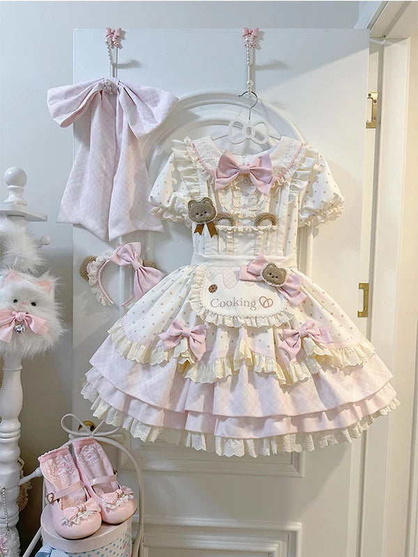 Pink bear OP dress set with an apron, bows and layered ruffles displayed on a hanger.