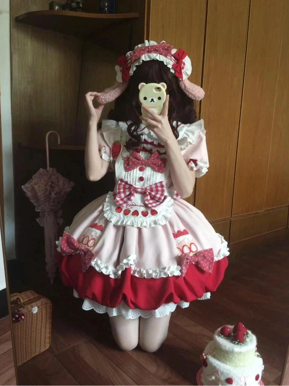 Pink strawberry OP dress set with a doll collar, bows and a full layered skirt worn by a model.