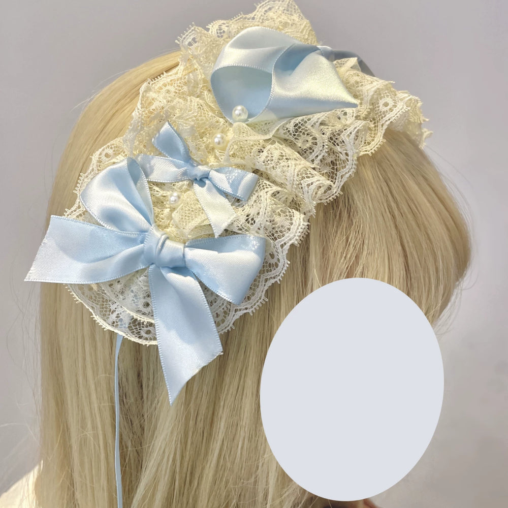 Blue ribbon-edged headwear pieces with bow details arranged on white lace.