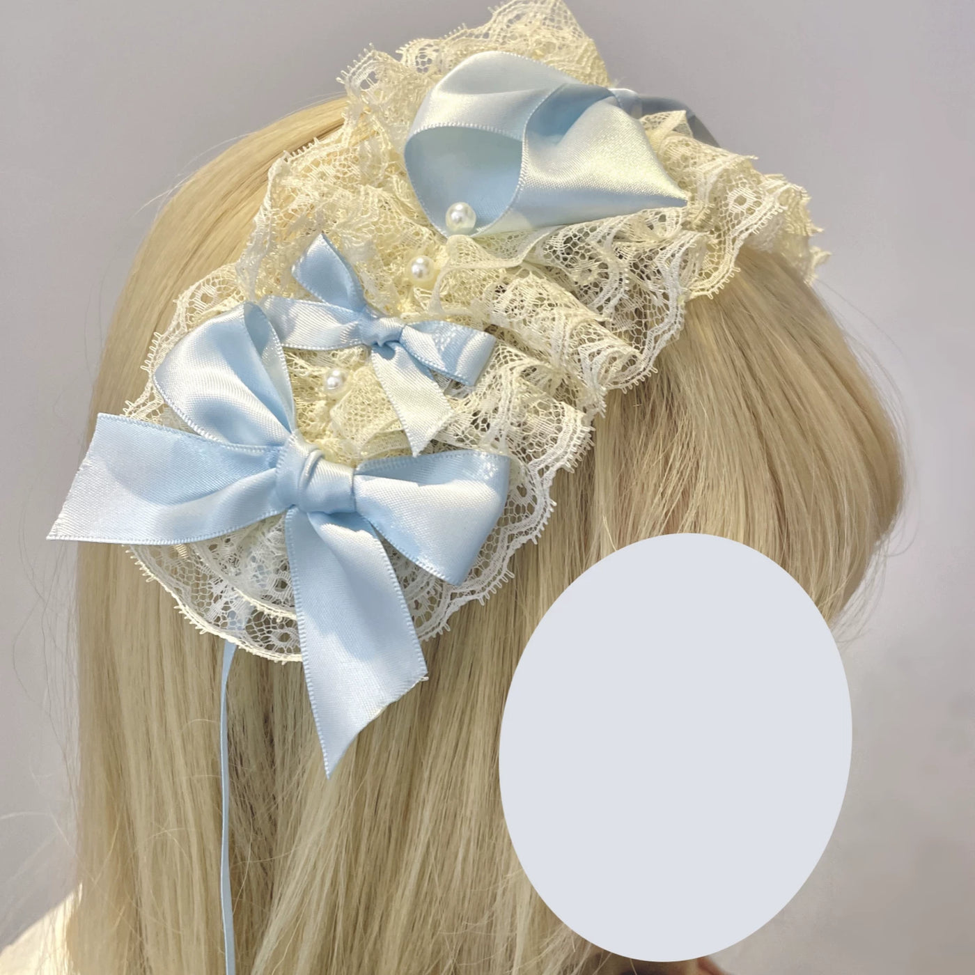Blue ribbon-edged headwear pieces with bow details arranged on white lace.