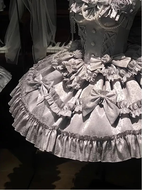 Silver JSK with rose motifs, layered ruffles, neck accessory and train bow on a mannequin.