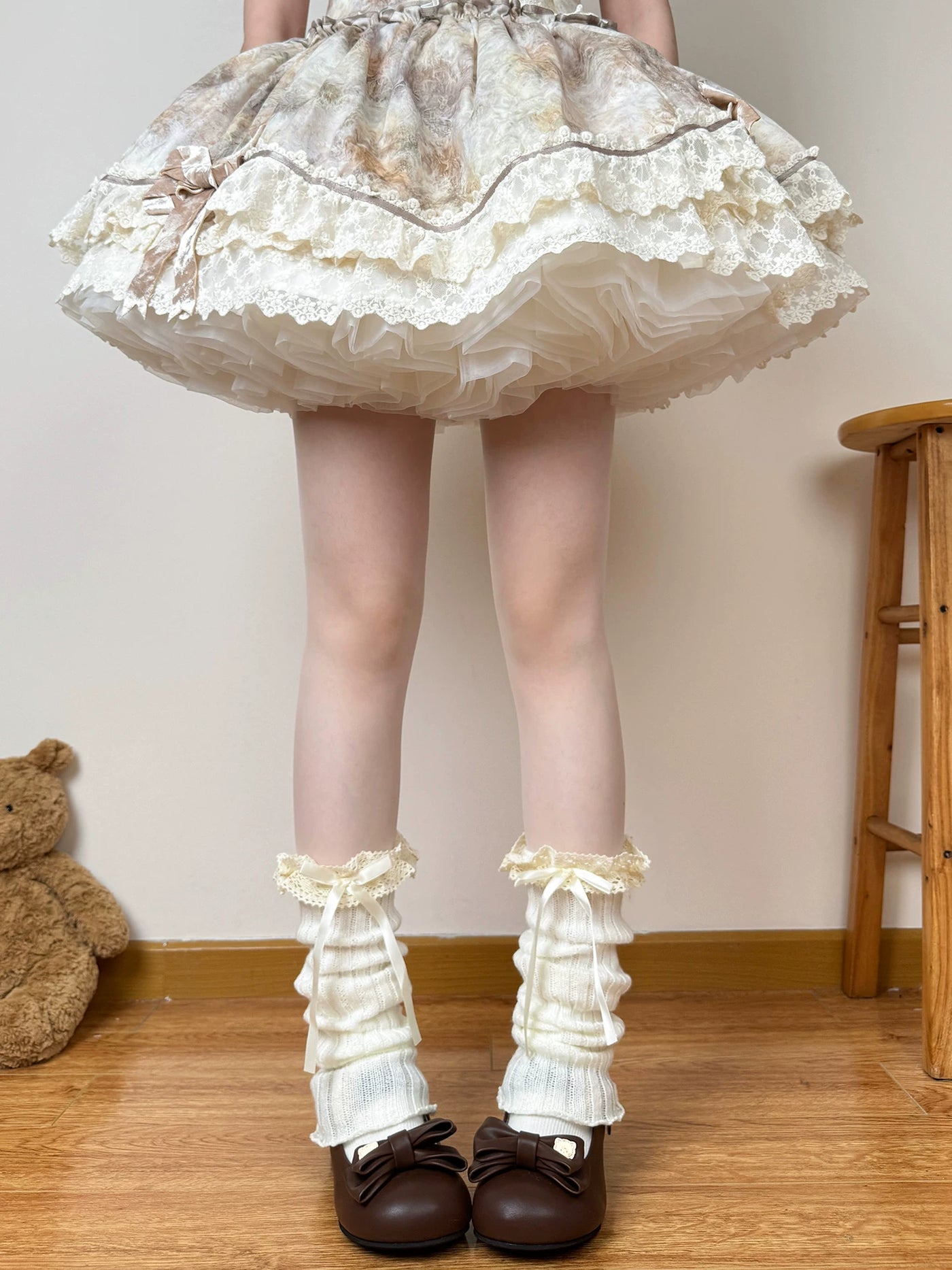 Off-white knit leg warmers with lace trim and bows styled over tights.