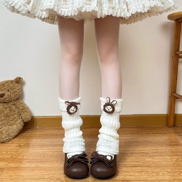 Off-white teddy-bear cuff leg warmers shown with a lace-trimmed skirt and brown shoes.