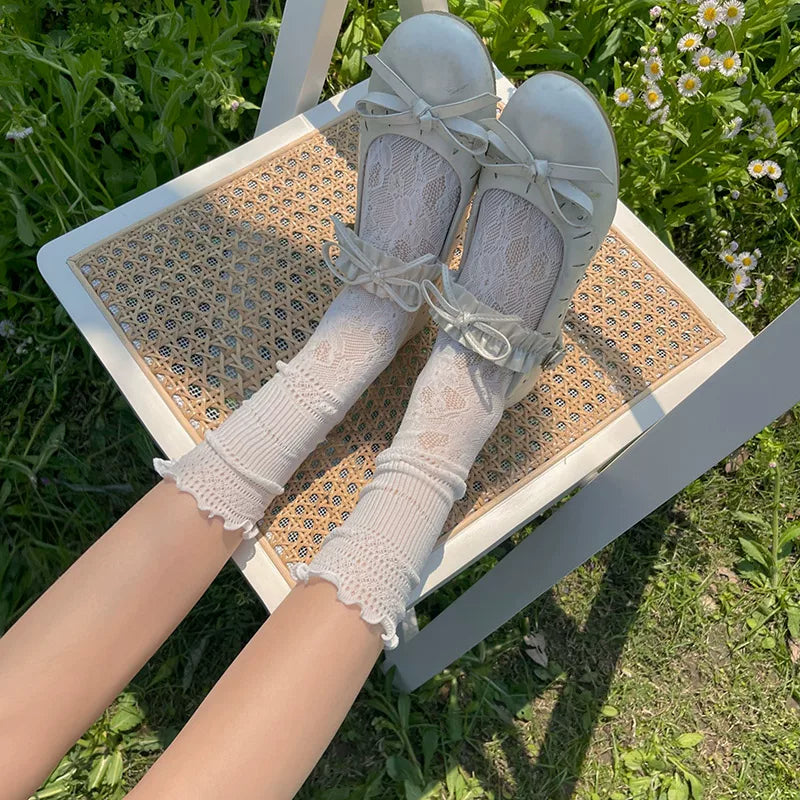 White lace-trimmed slouch socks worn with white bow shoes outdoors.