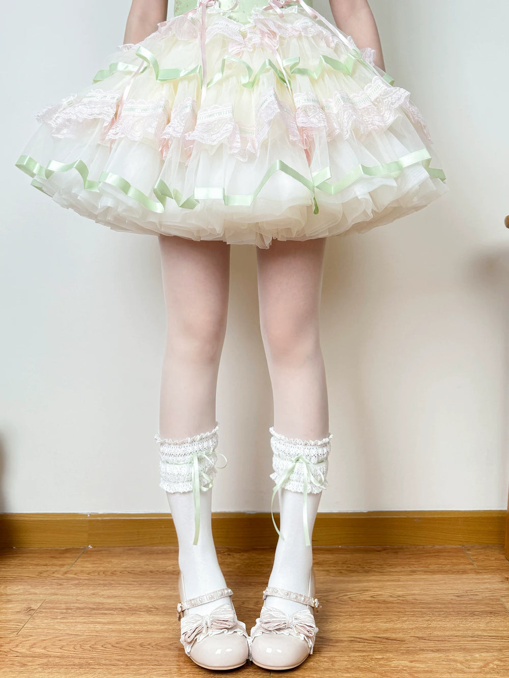 Model wearing white lace-trimmed socks with green ribbon ties and white shoes.