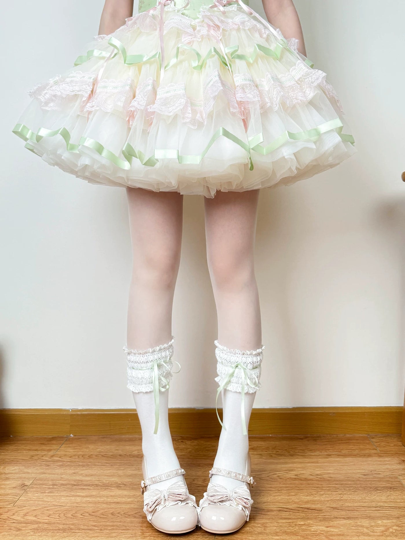 Model wearing white lace-trimmed socks with green ribbon ties and white shoes.