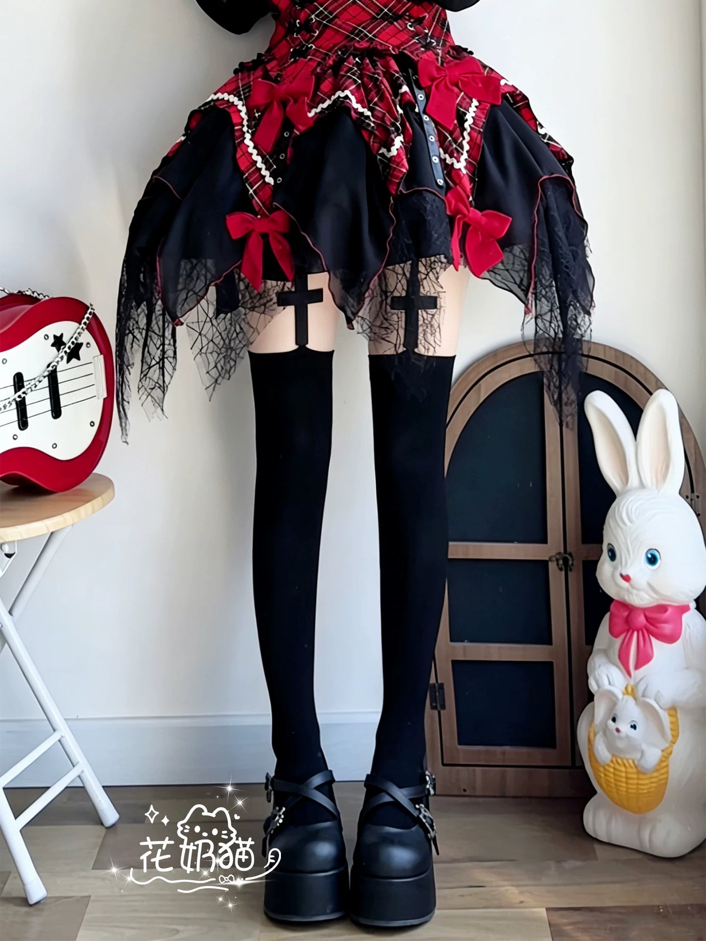 Black thigh-high socks with cross-shaped suspender straps styled beneath a red-and-black ruffled skirt.