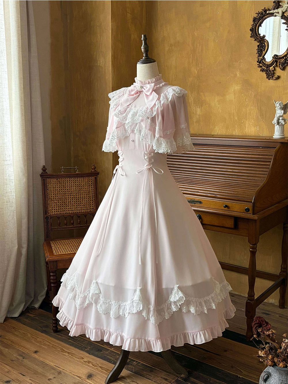 Pale pink dress with lace-trimmed cape and ruffled hem