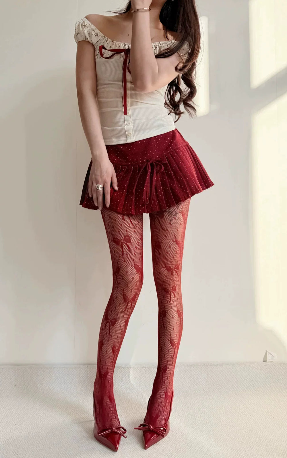 Black fishnet tights with scattered polka dots and bow motifs styled beneath a black skirt.