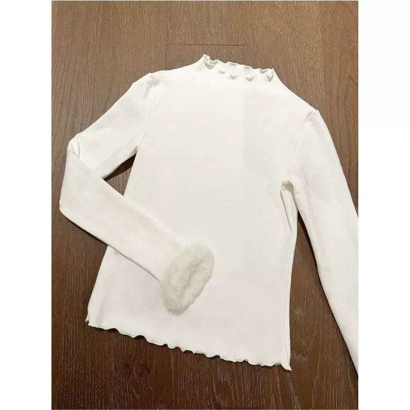 White long-sleeve top with a ruffled neckline and scalloped hem laid flat
