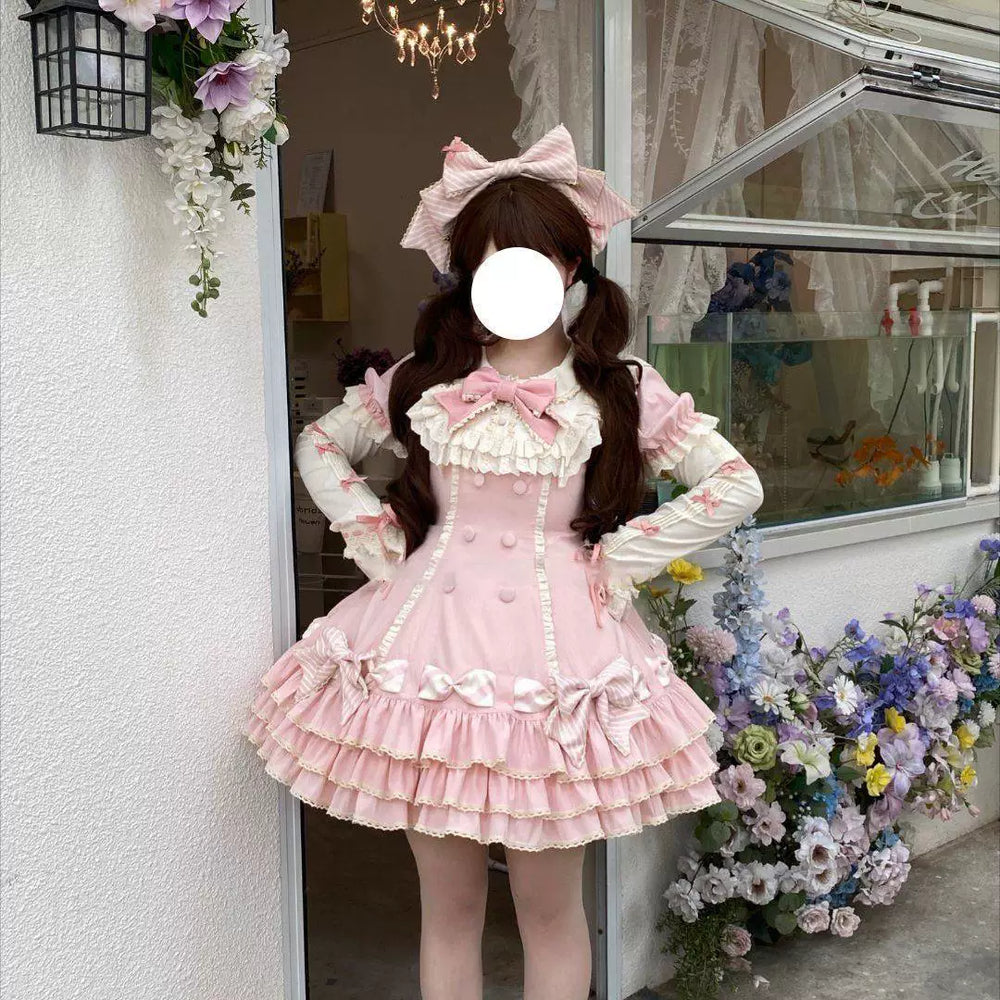 Pink short-sleeve OP dress with ruffled bib, bows and tiered skirt styled in a mirror