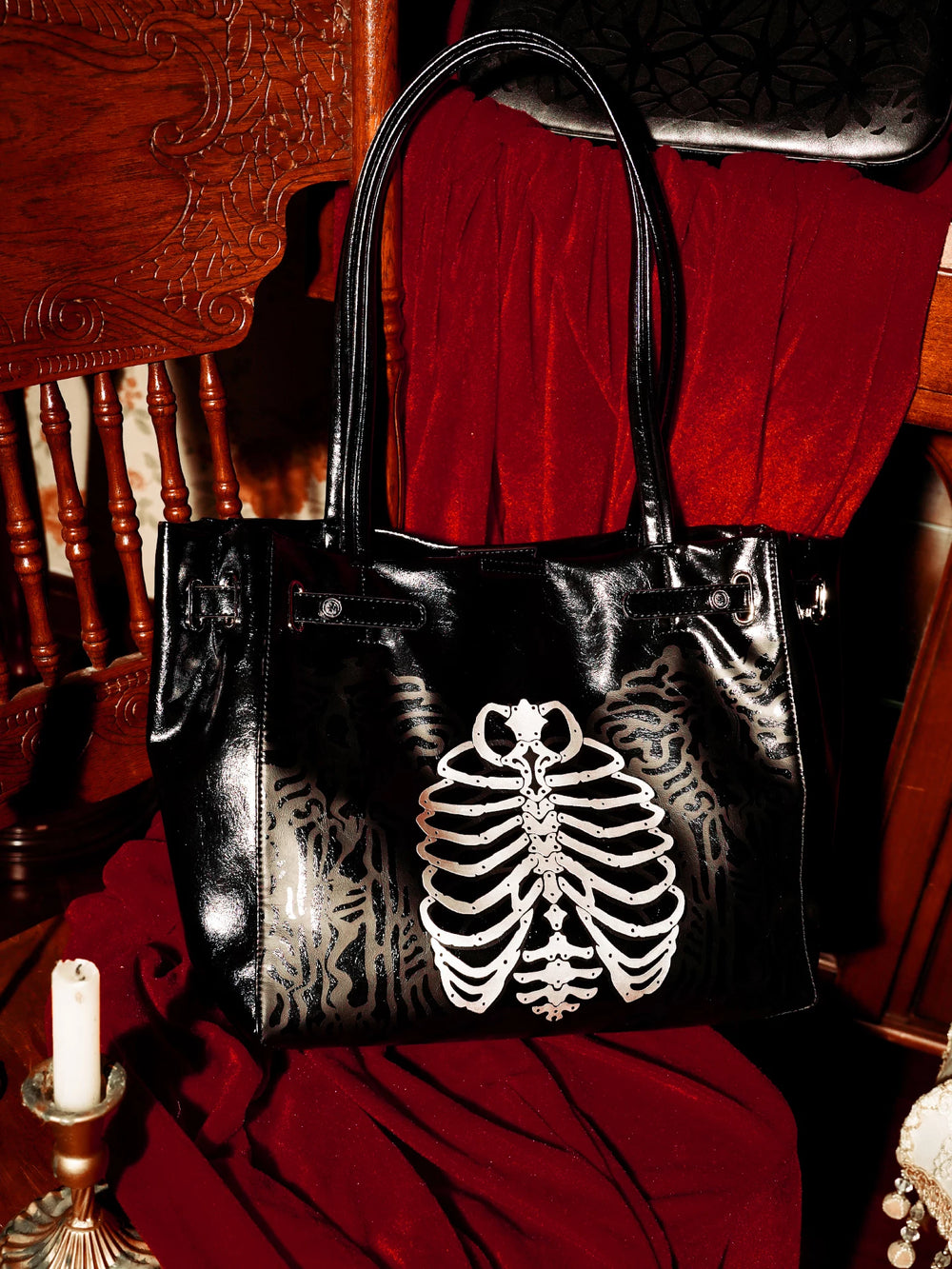 Black tote bag with a white skeleton ribcage graphic against a red backdrop.