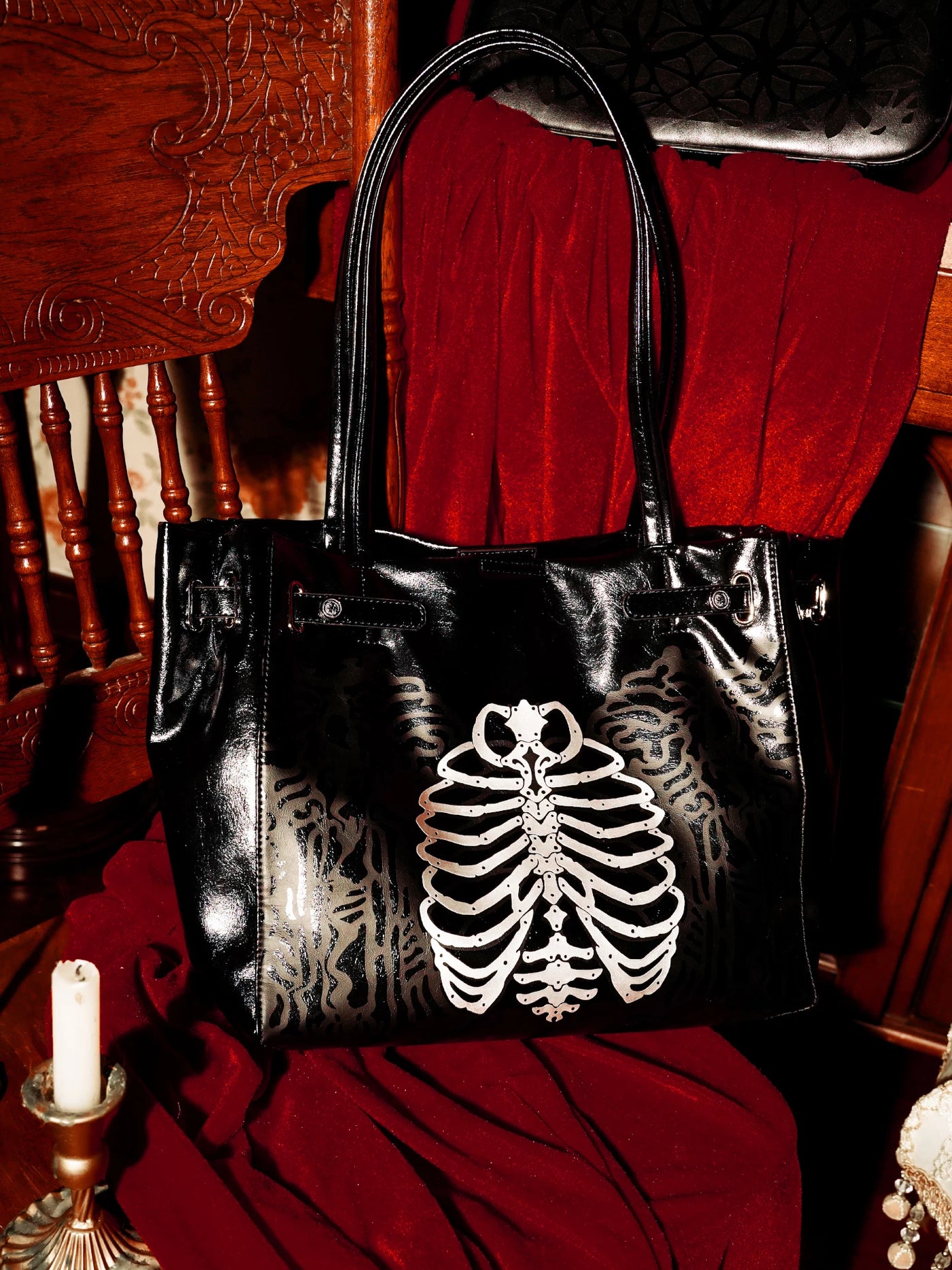 Black tote bag with a white skeleton ribcage graphic against a red backdrop.