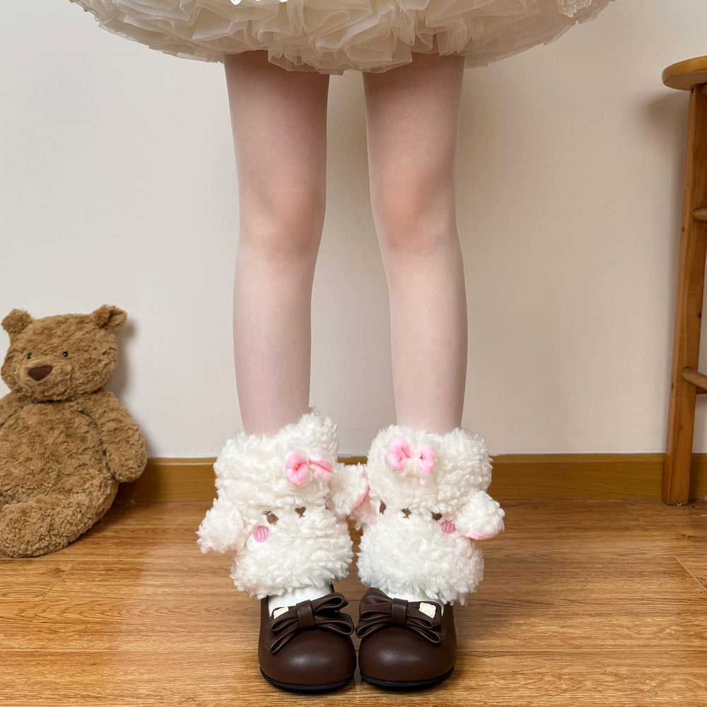 White plush sheep sock covers with pink bows shown on the lower legs.