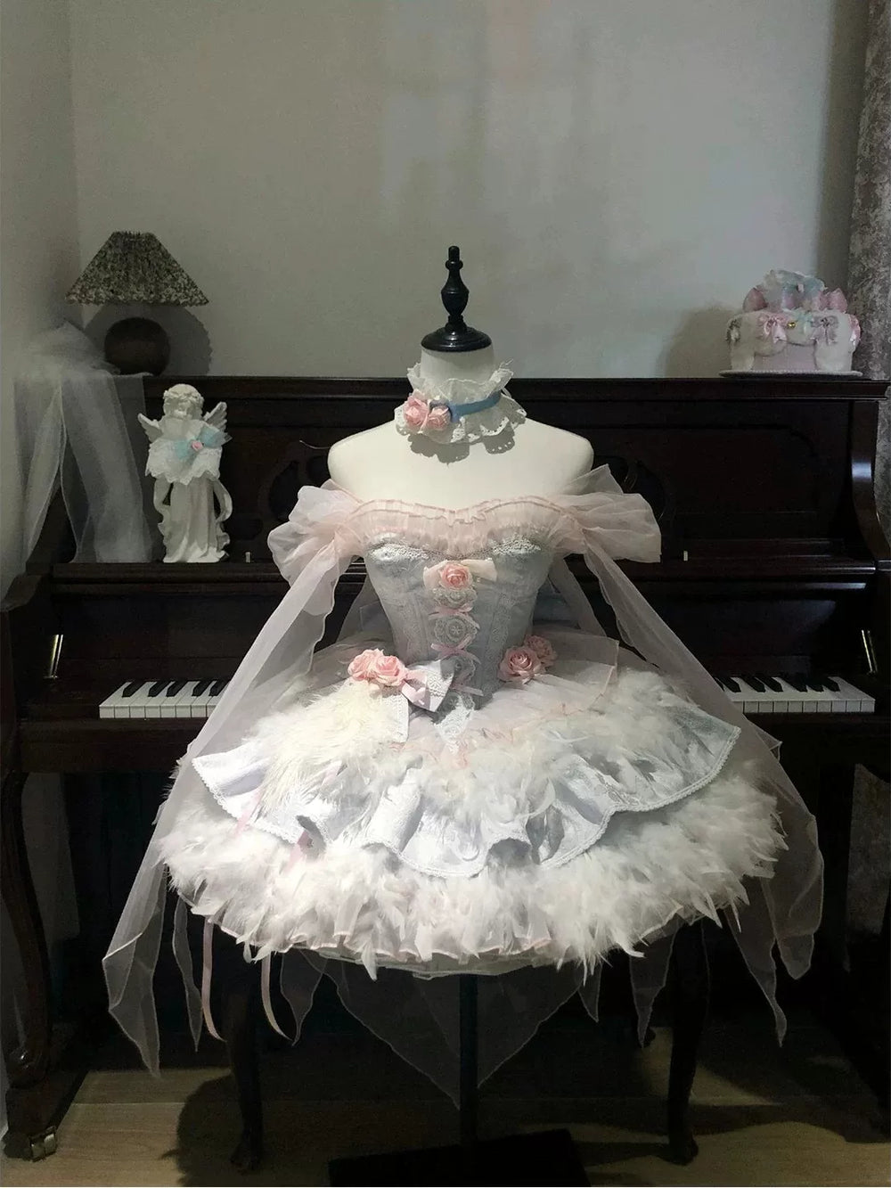 White JSK dress with feather trim and lace details displayed on a mannequin.