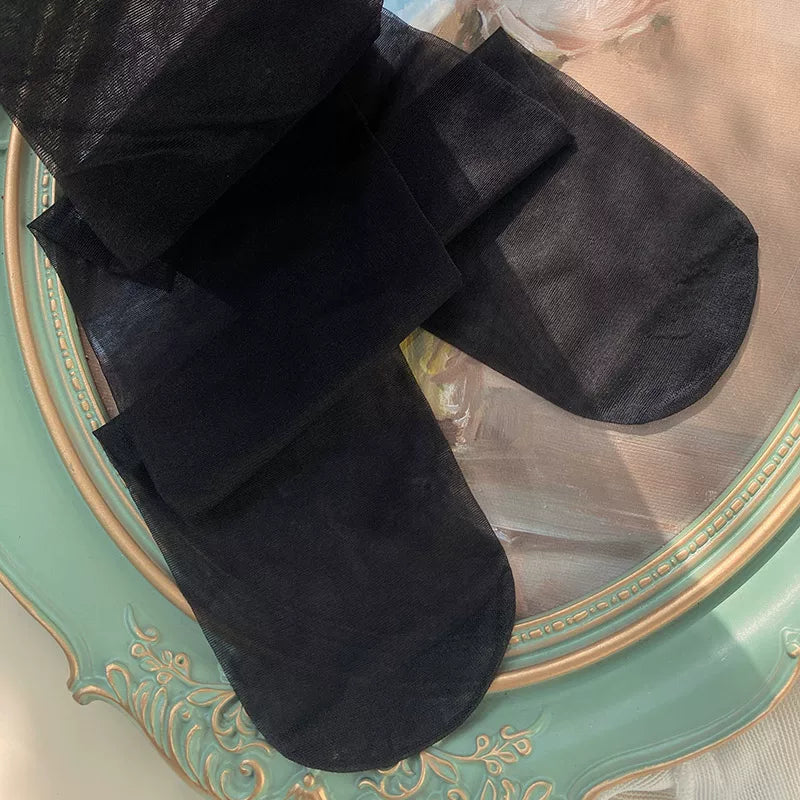 Black sheer footed tights laid flat on a decorative tray