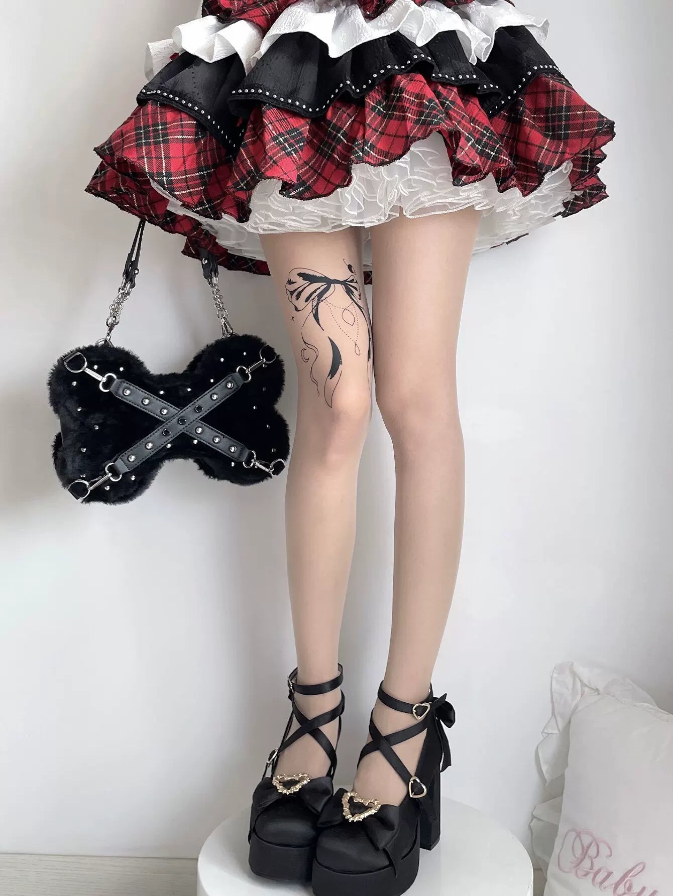 Skin-tone tights styled with a black and red plaid coordinate.