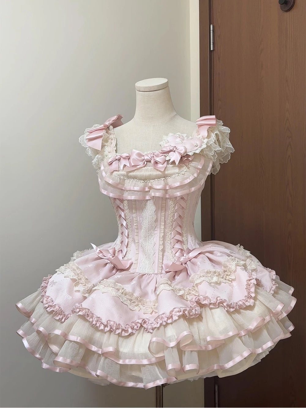 Creamy pink JSK dress with satin ribbons, bows, lace and heart detail on a mannequin