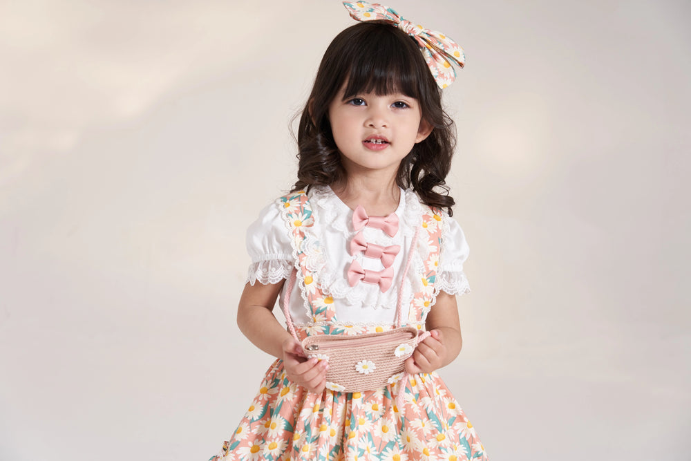 Child wearing a white puff-sleeve T-shirt beneath a floral dress.