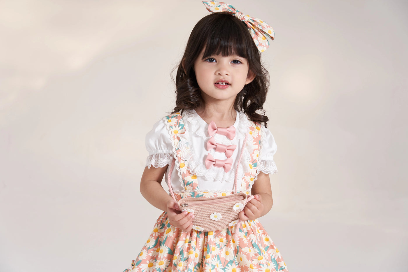 Child wearing a white puff-sleeve T-shirt beneath a floral dress.