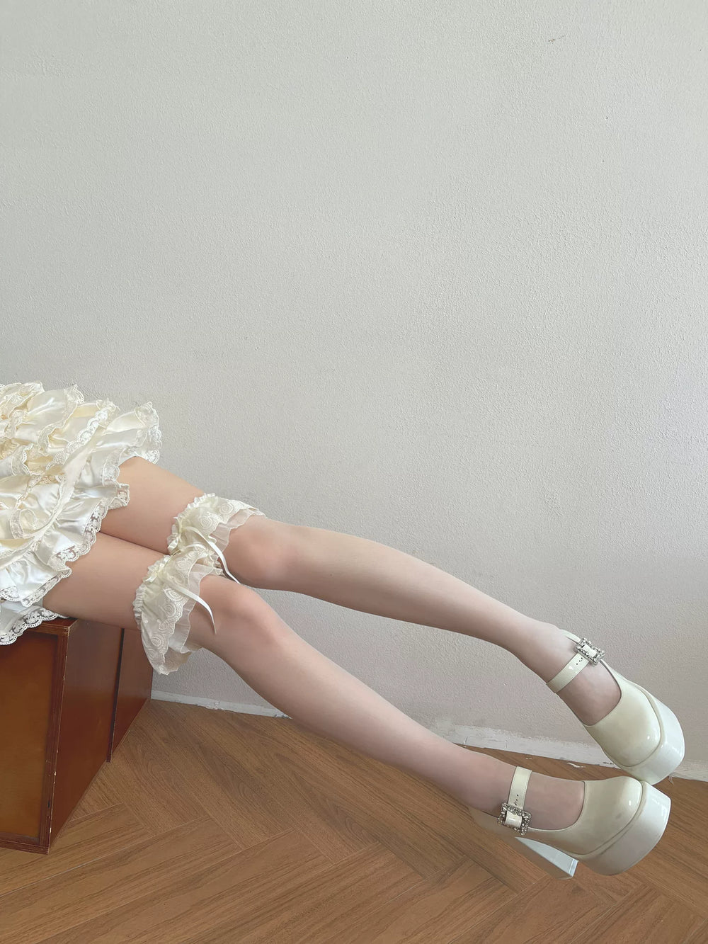 White over-the-knee socks with layered ruffles and scalloped lace edging worn with white platform shoes.
